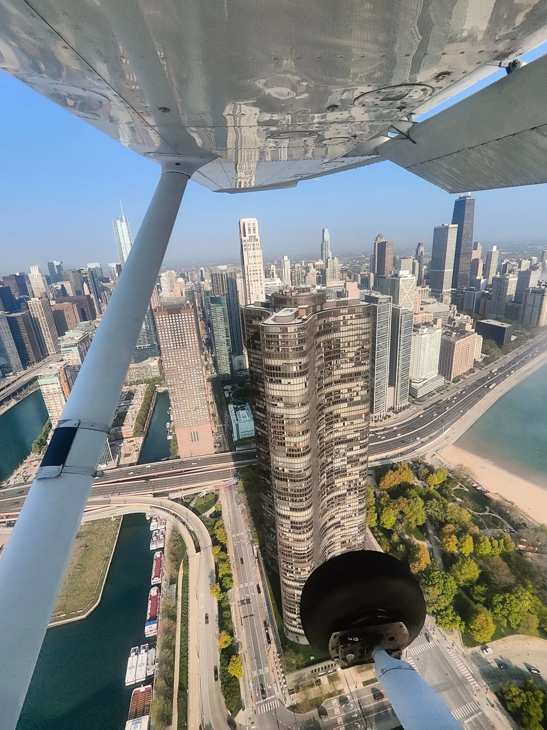从小型飞机机翼下俯瞰湖滨城市的高楼与沙滩